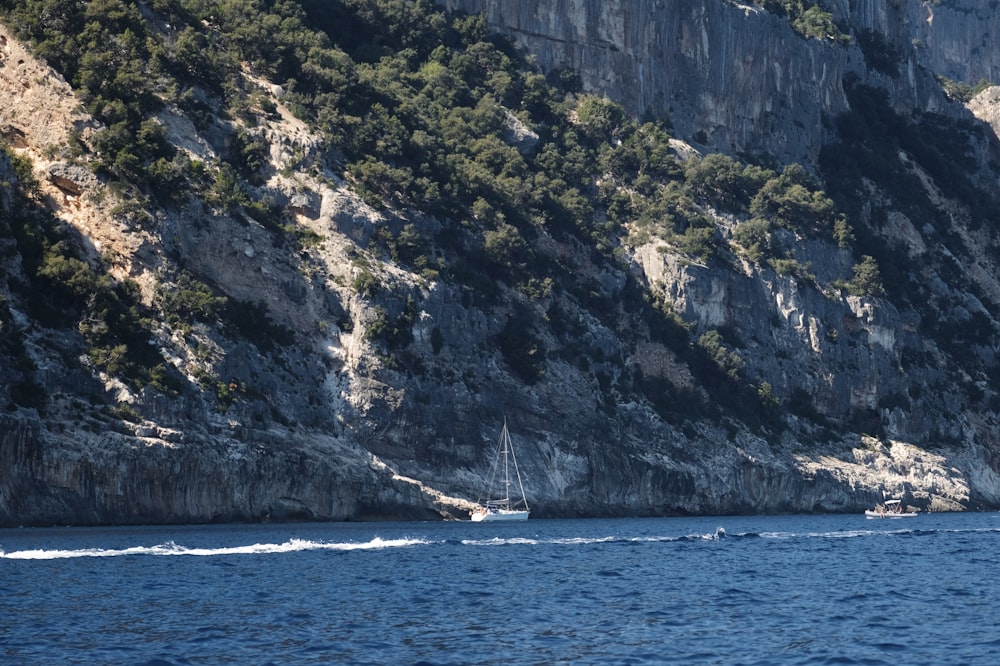 a boat traveling down a body of water near a mountain