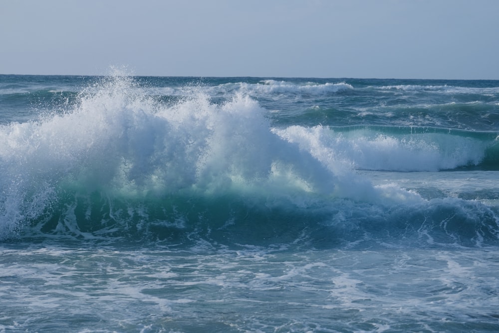 a large wave crashing into the ocean on a sunny day