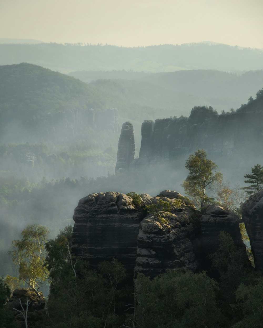 a view of a mountain range with fog in the air