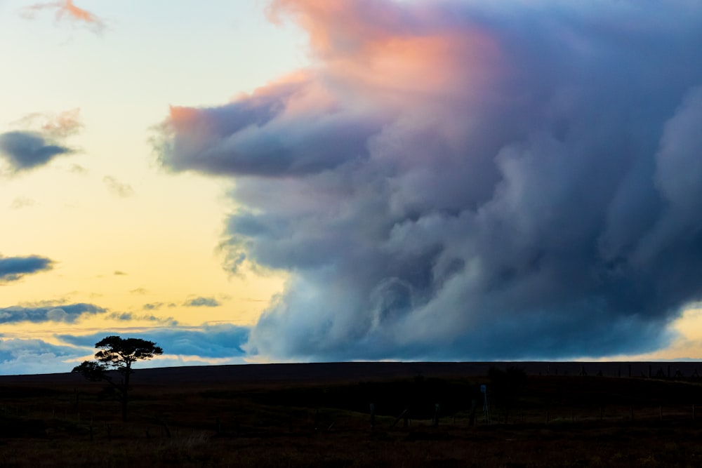 a large cloud is in the sky over a field