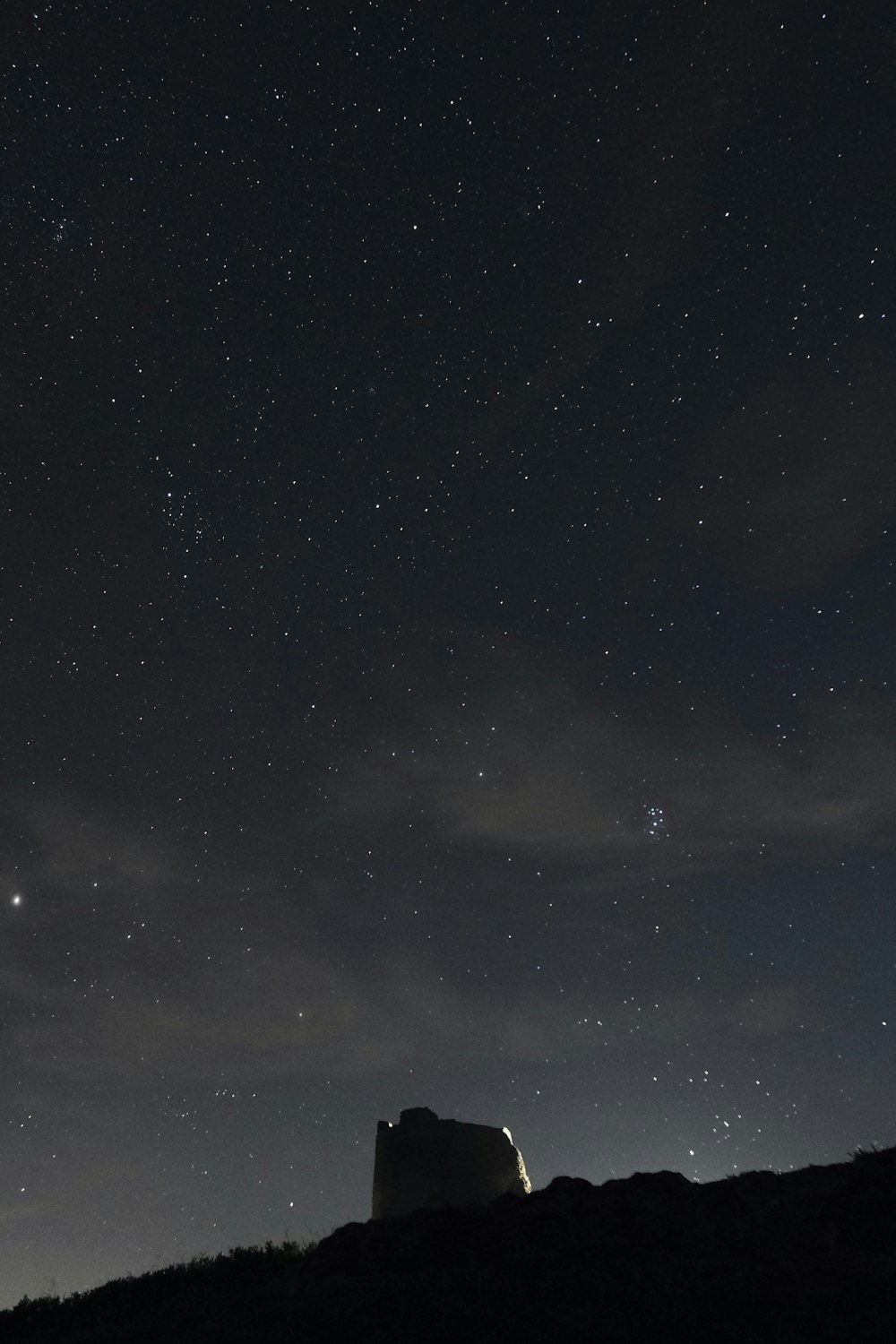 the night sky with stars above a hill