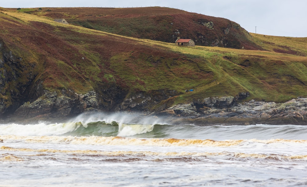 a large body of water with a house on a hill in the background