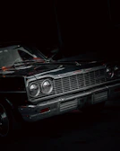 A shiny black classic car model with red accents under soft lighting