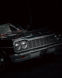 A vintage car with polished chrome details set against a black backdrop.