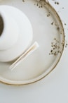 a white vase sitting on top of a white plate