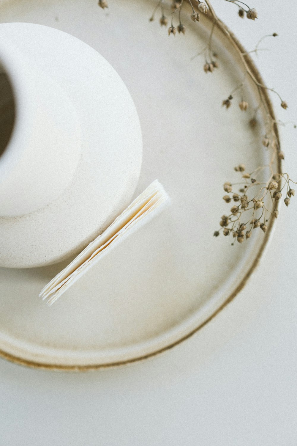 a white vase sitting on top of a white plate