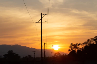 the sun is setting behind a telephone pole