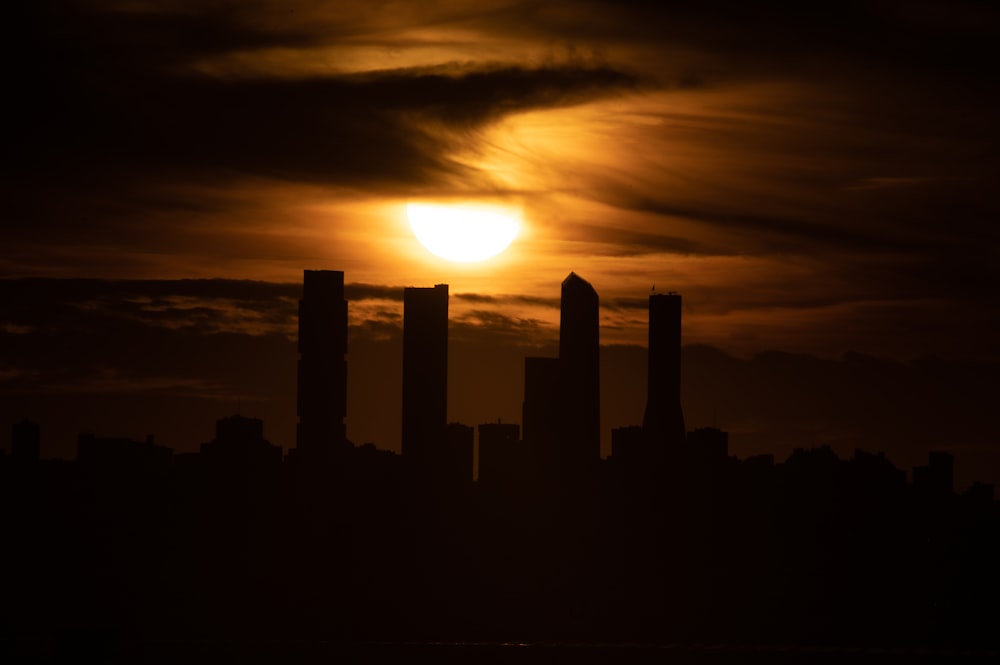 the sun is setting over a city with tall buildings