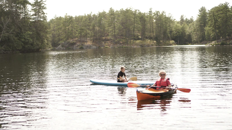Two campers kayaking together on the camp lake