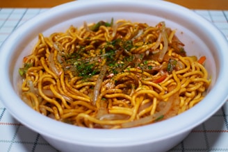 A vibrant bowl of vegetarian noodles topped with fresh herbs.