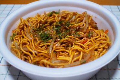 A vibrant bowl of vegetarian noodles topped with fresh herbs.