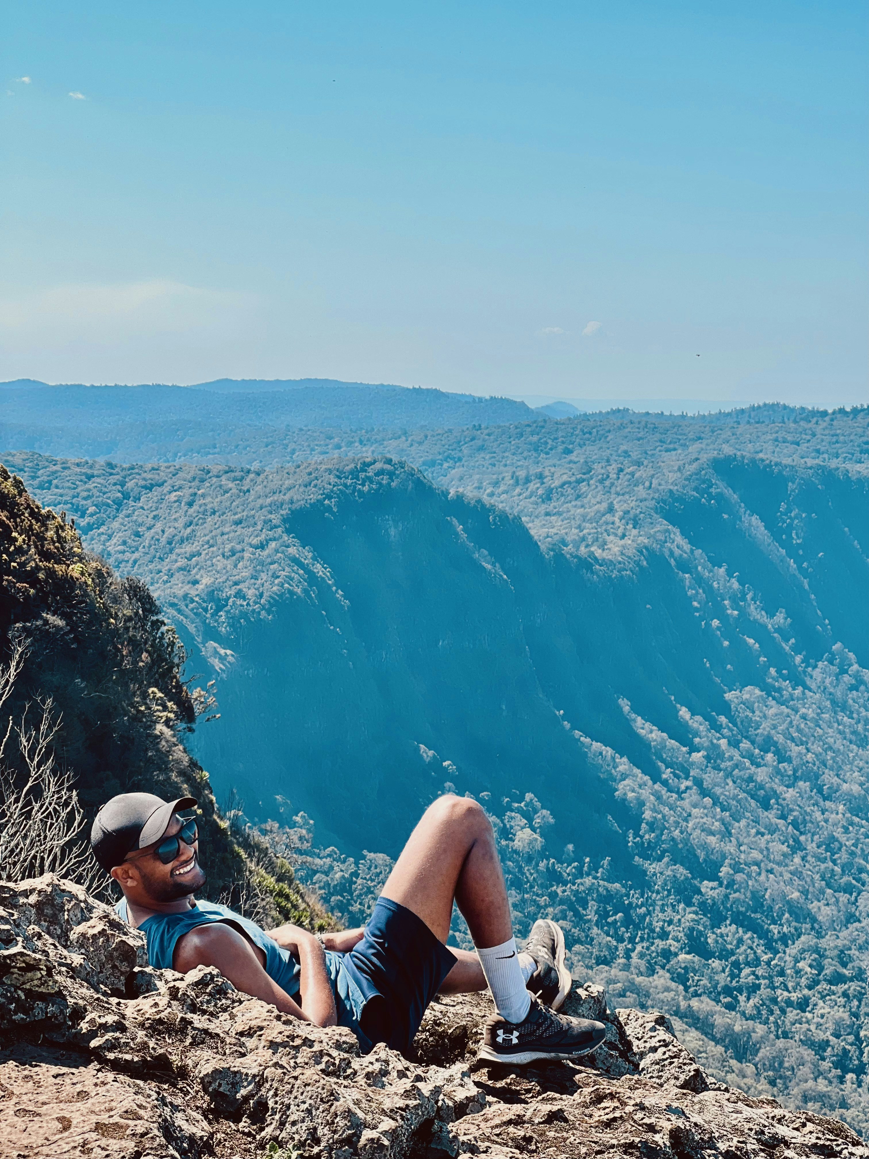 Ein Mann sitzt auf einem Berg neben einer Klippe