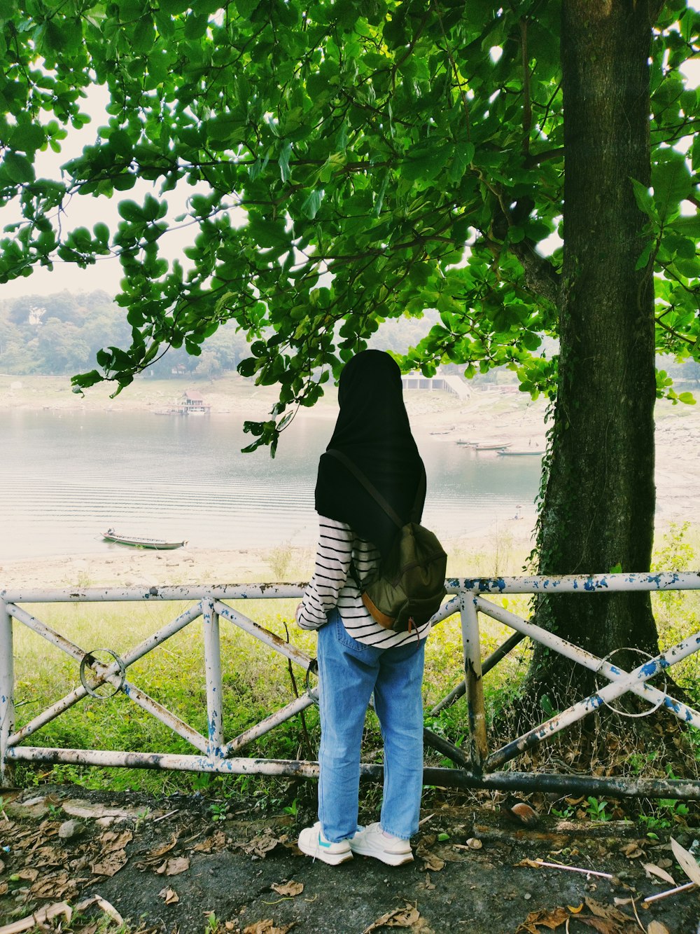 a person leaning on a fence near a tree