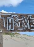 a wooden sign on a beach with the word brave written on it
