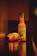 Two bottles of organic carrot and apple juice are shown, with one bottle standing upright and the other lying on its side. The setting has a warm, dim lighting that creates a cozy atmosphere.
