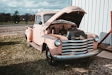 A mechanic inspecting a vintage truck in the yard.