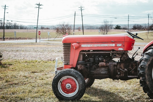 an old red tractor parked in a field