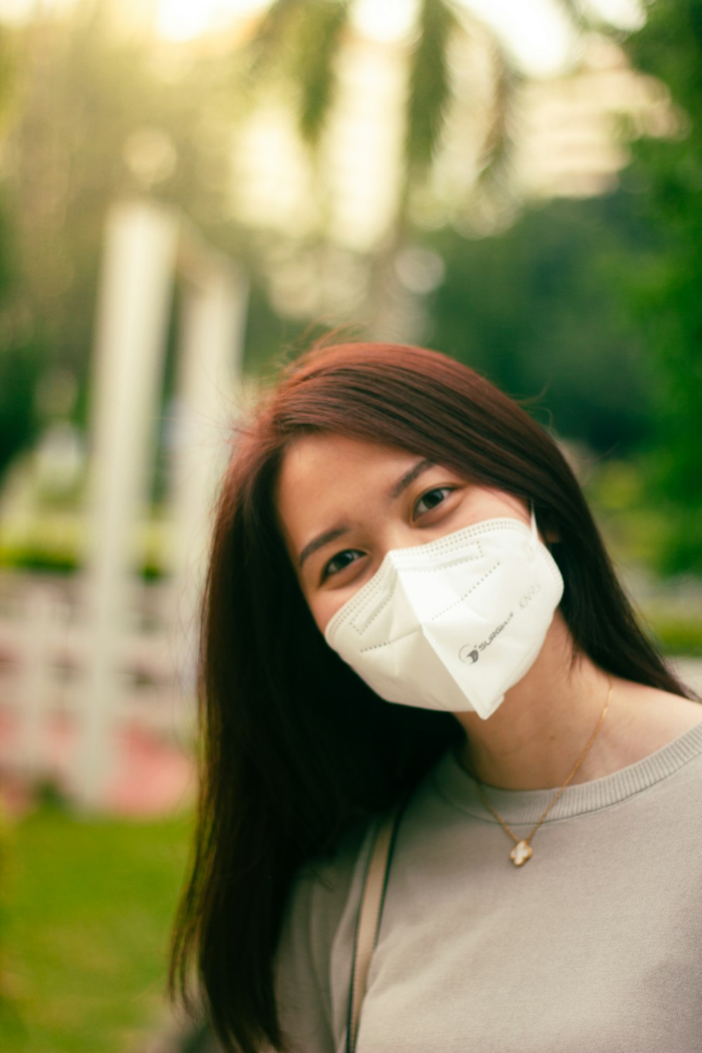 uma mulher usando uma máscara facial em um parque