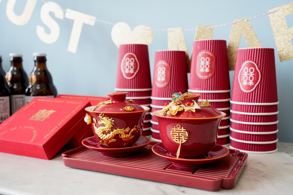 a table topped with red cups and saucers