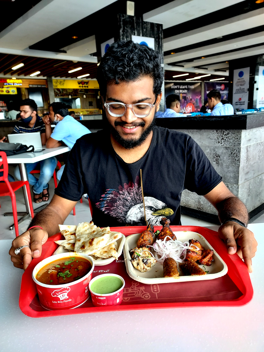 a man sitting at a table with a tray of food