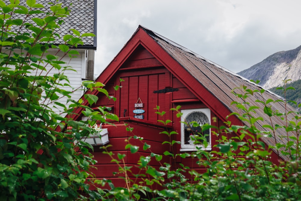 a red house with a window and a mountain in the background