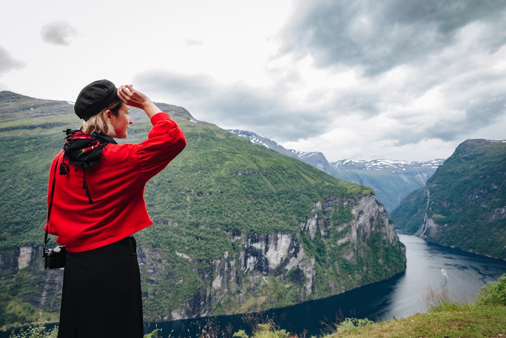 a woman standing on top of a lush green hillside