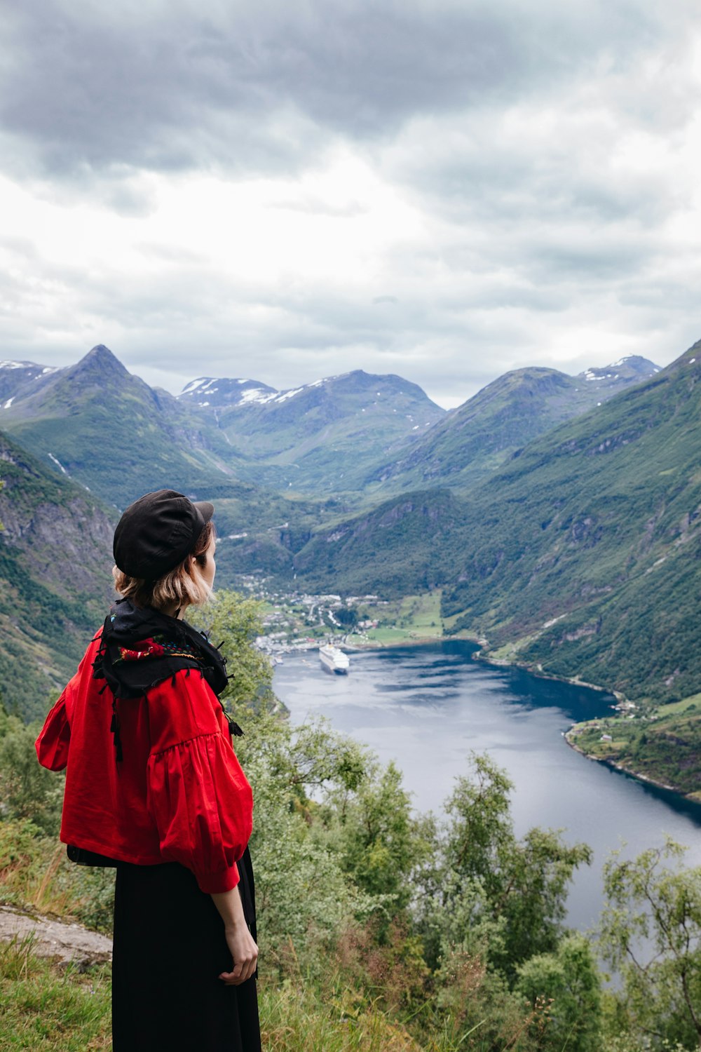 a woman standing on top of a lush green hillside