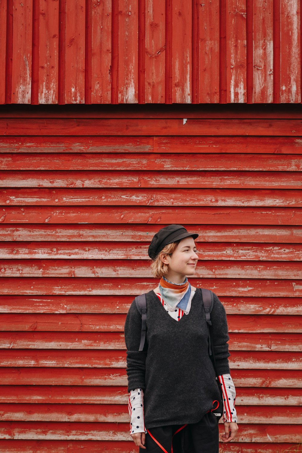 a young girl standing in front of a red wall