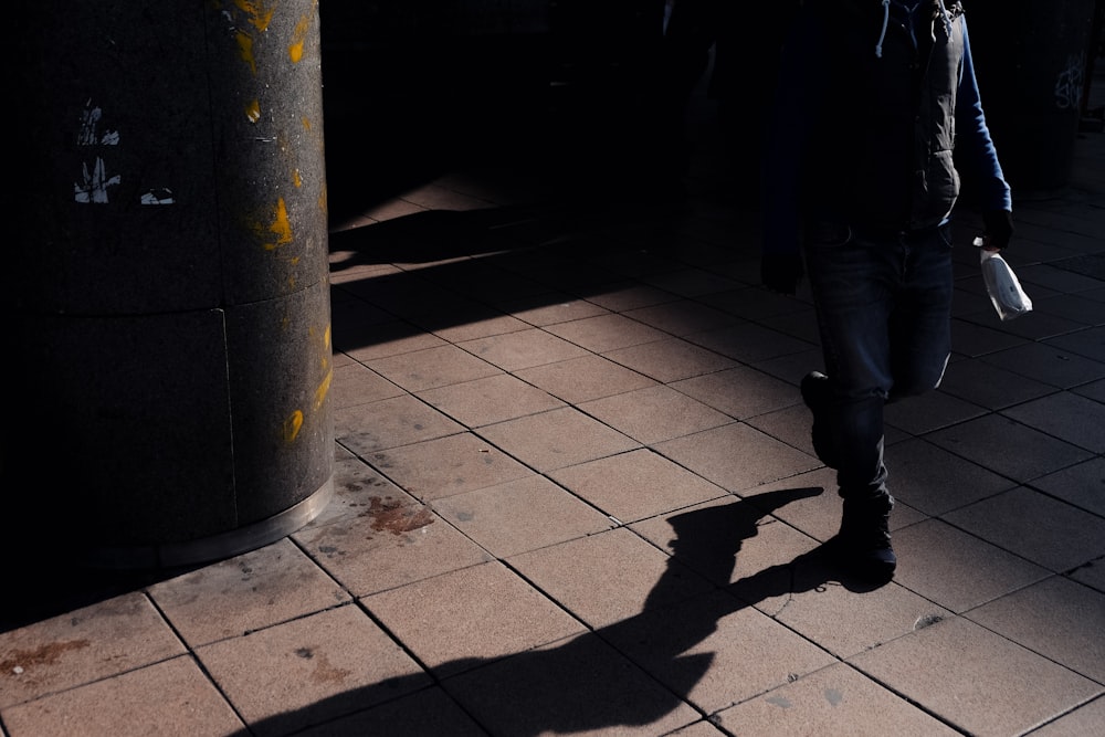 a man walking down a sidewalk in the dark