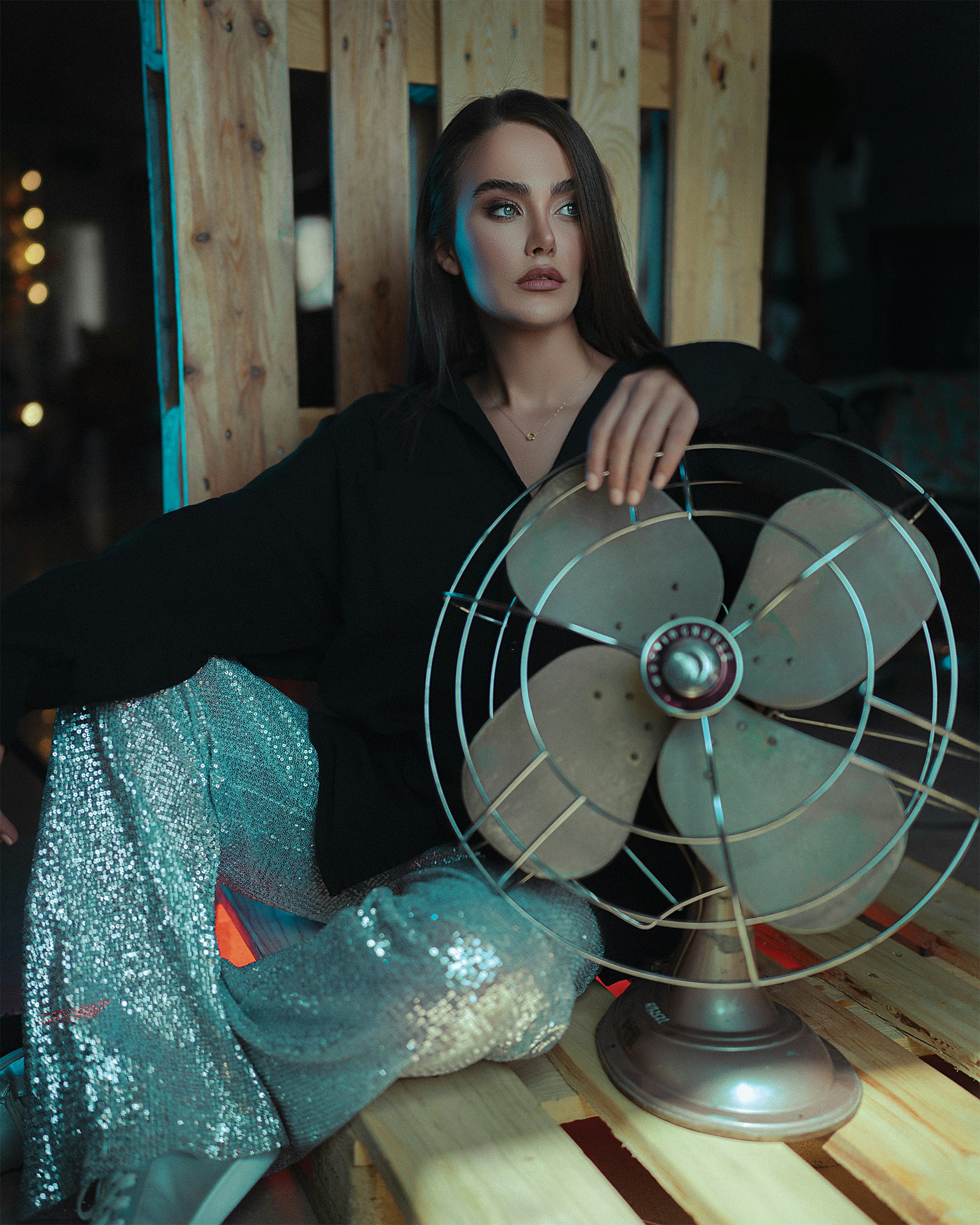 a woman sitting on a bench next to a fan