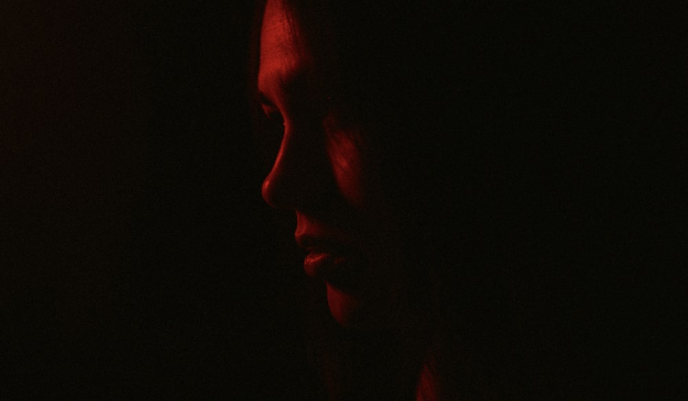 a woman in the dark with a red light on her face