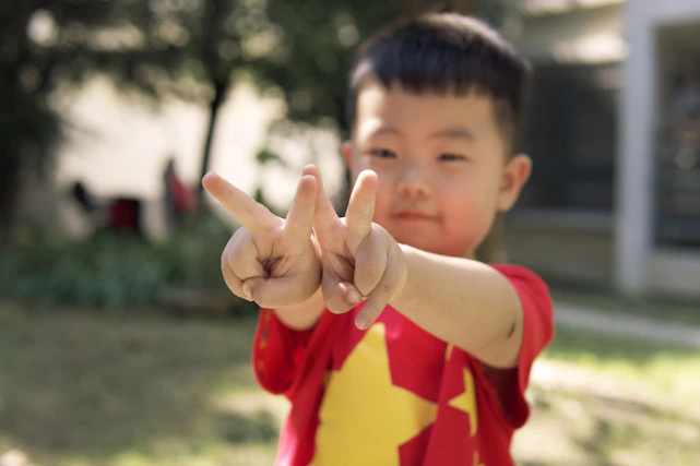 a young boy making a peace sign with his fingers