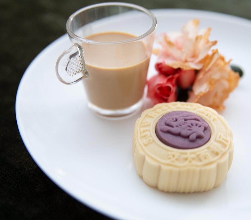 a white plate topped with a cookie next to a cup of coffee