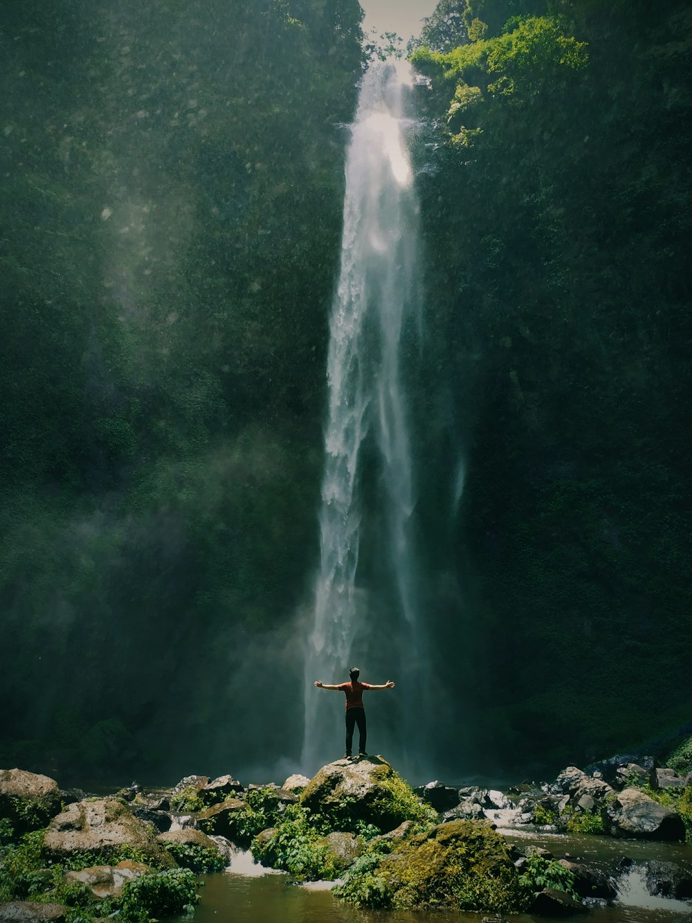 a man standing in front of a waterfall