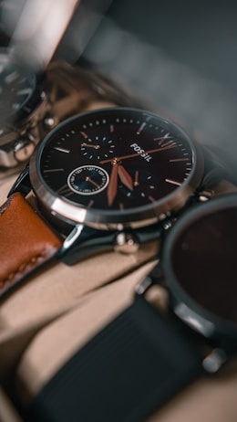 A close-up view of a sophisticated wristwatch with a black dial and a brown leather strap. The watch features intricate details, including multiple sub-dials and silver accents. The focus is on the craftsmanship and elegance of the timepiece.