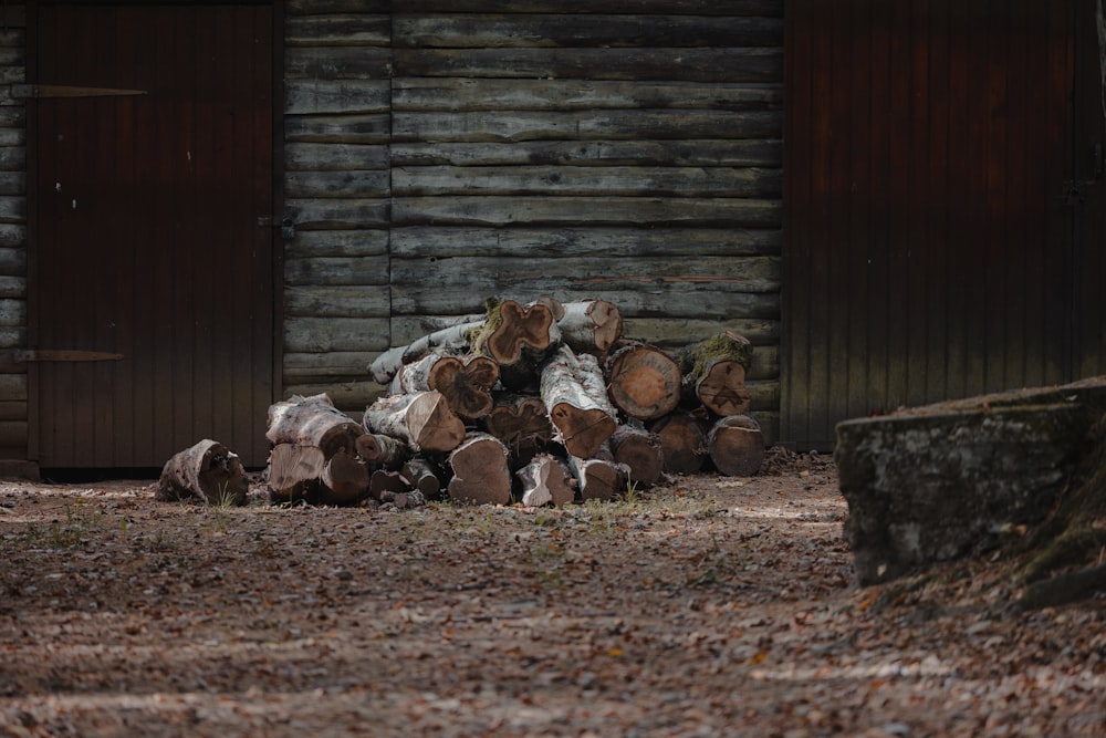 a pile of logs in front of a log cabin
