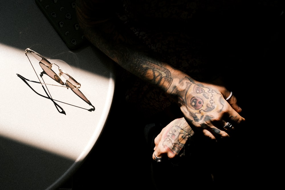 um homem com tatuagens em seu braço ao lado de uma mesa