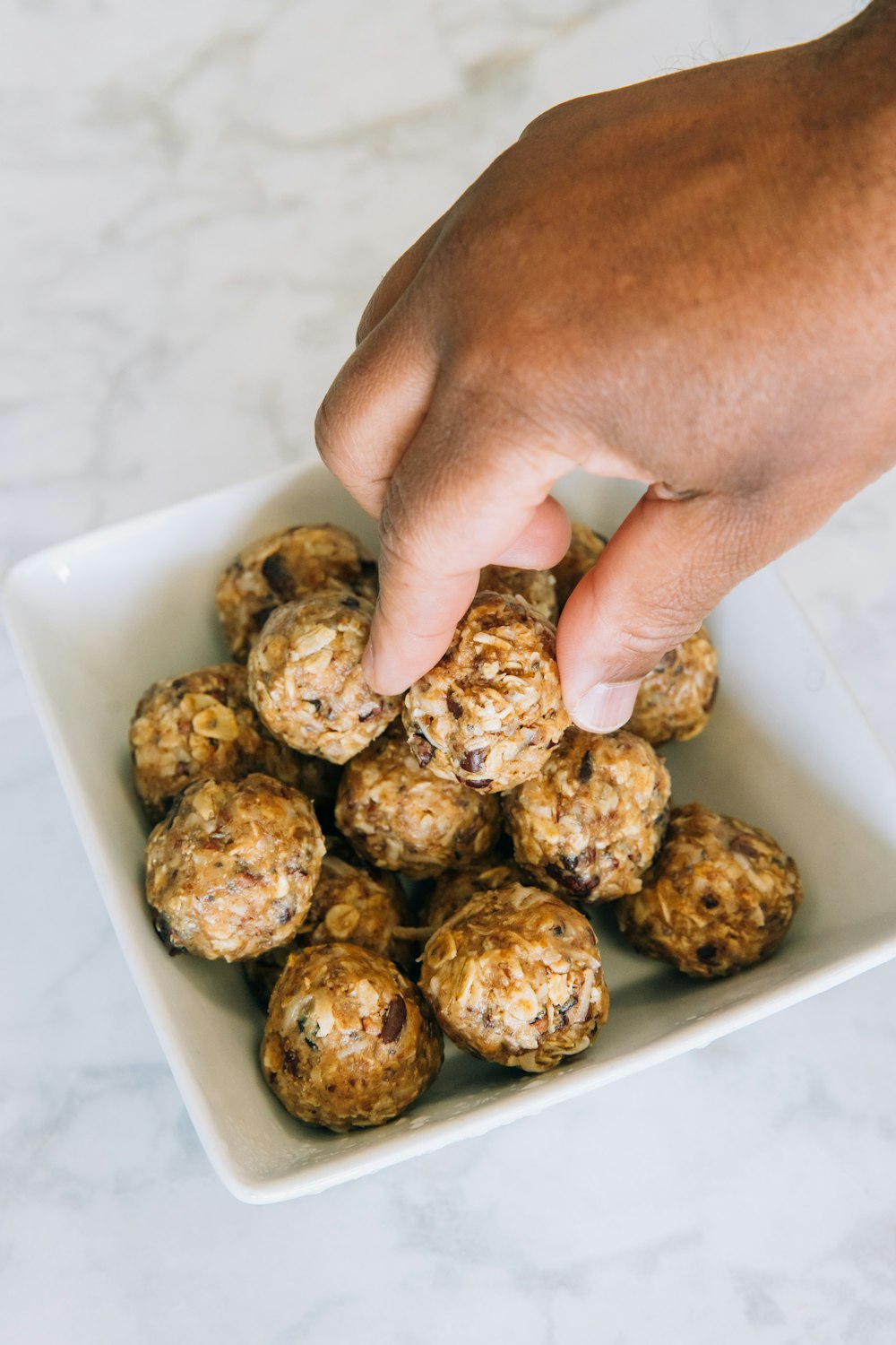 a person reaching for a ball of food in a bowl