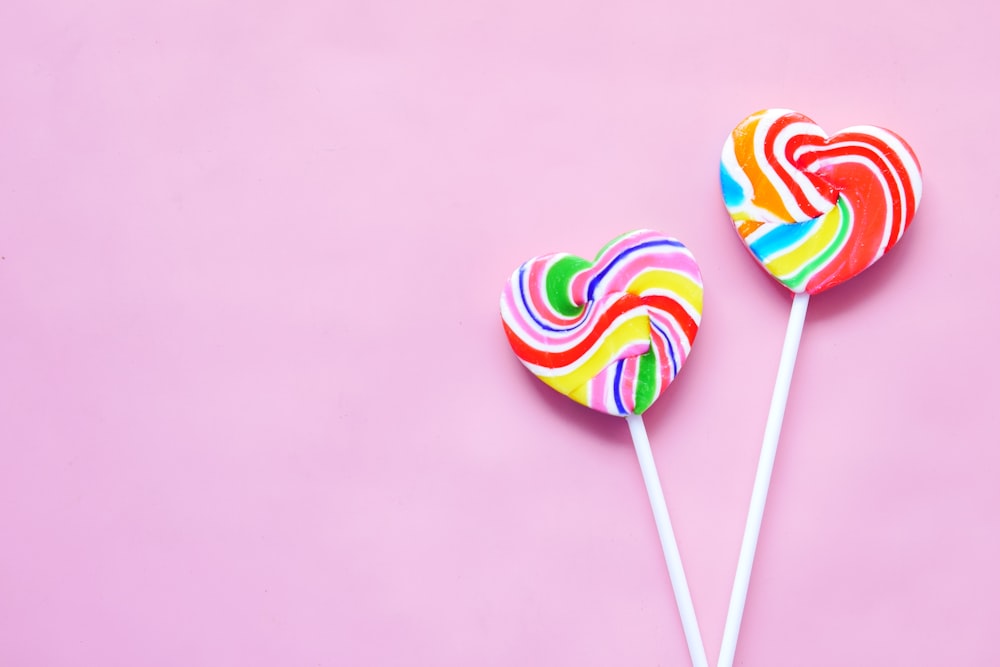 a couple of lollipops sitting on top of a pink surface