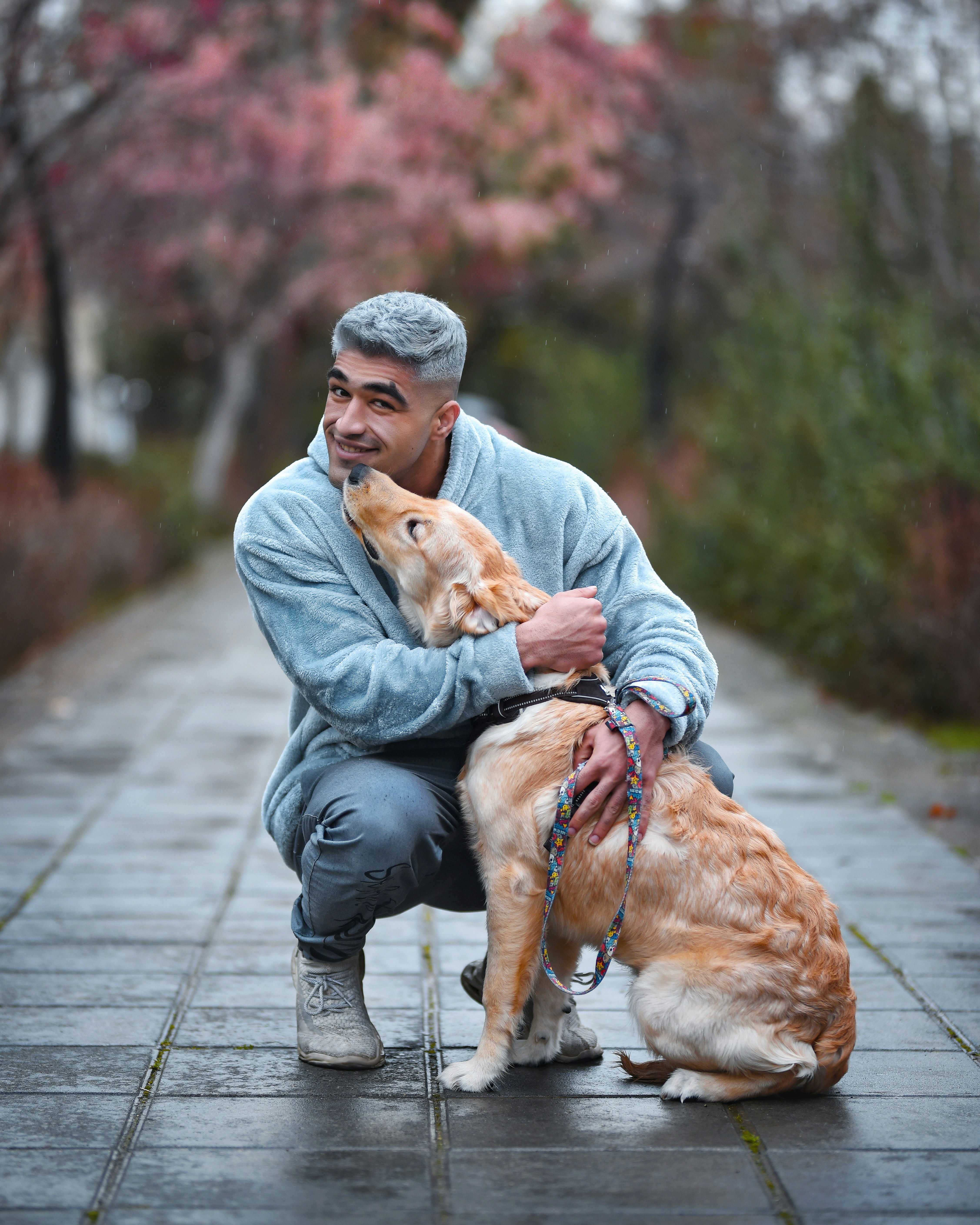 a man kneeling down with a dog on a leash