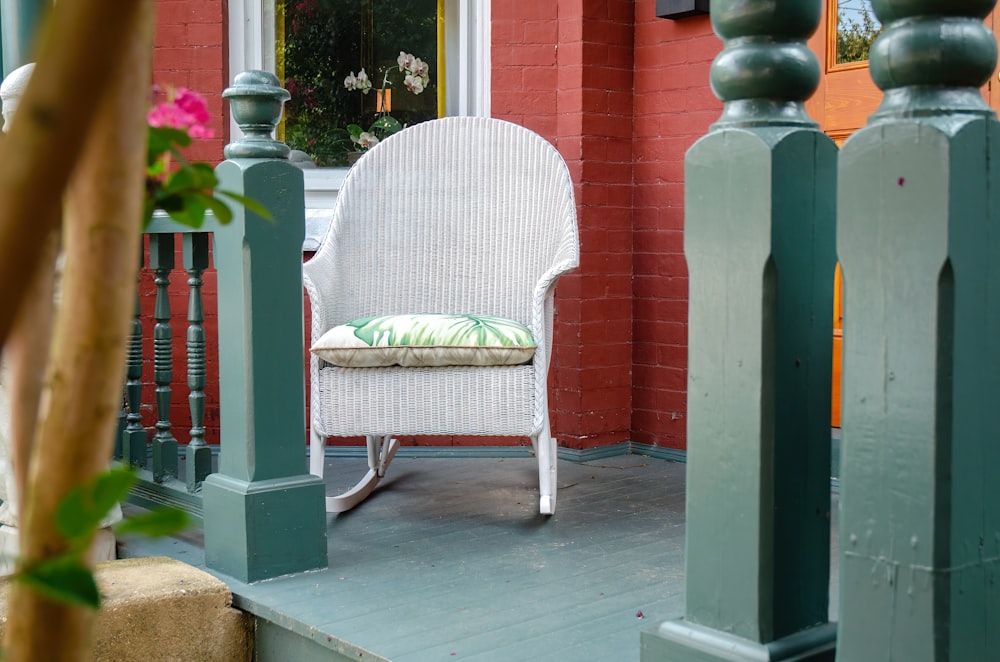 une chaise berçante blanche assise sur un porche