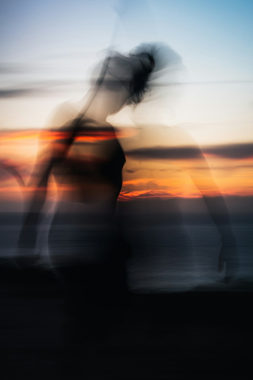 a blurry photo of a woman standing in front of a sunset