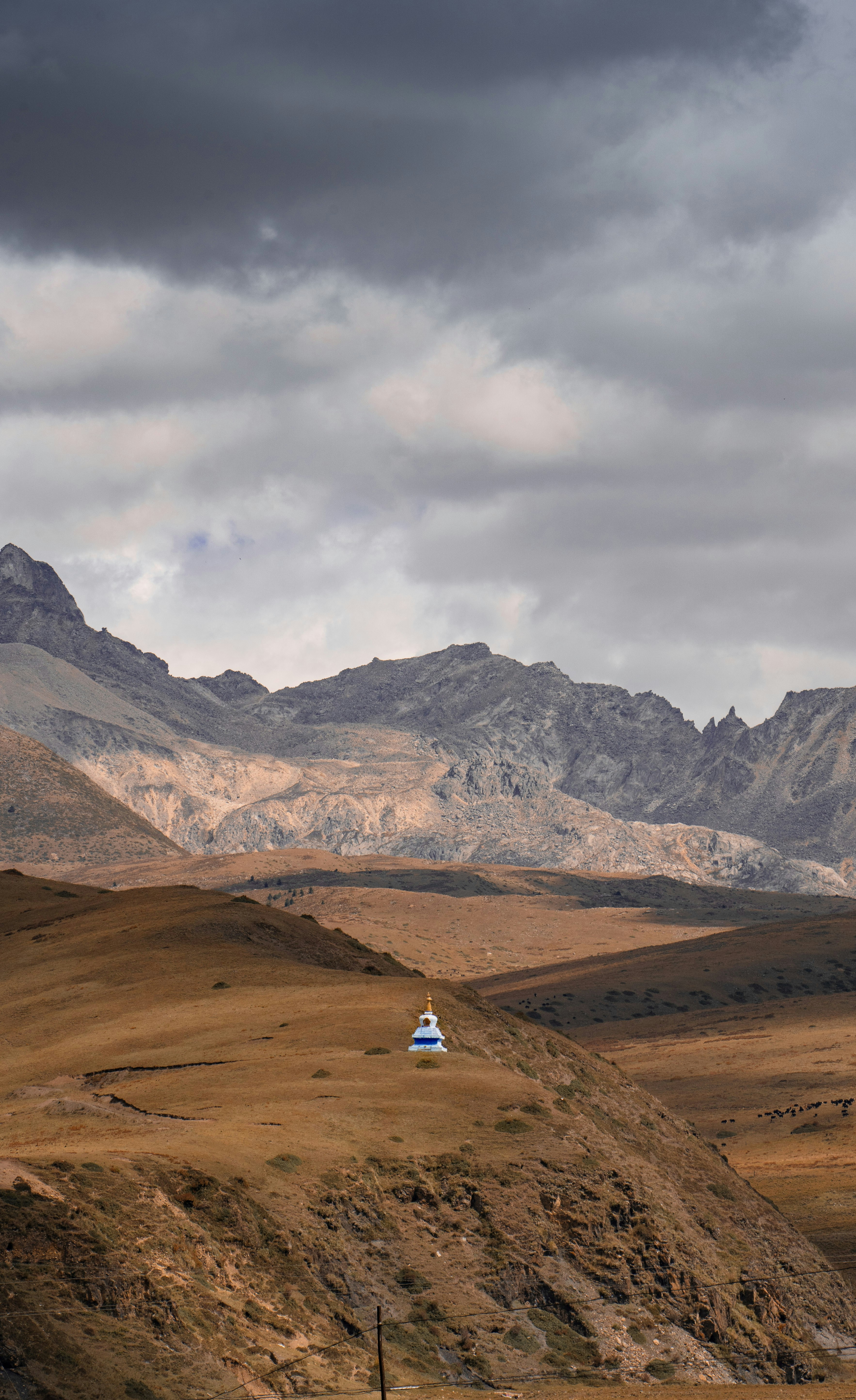 a small house in the middle of a field with mountains in the background