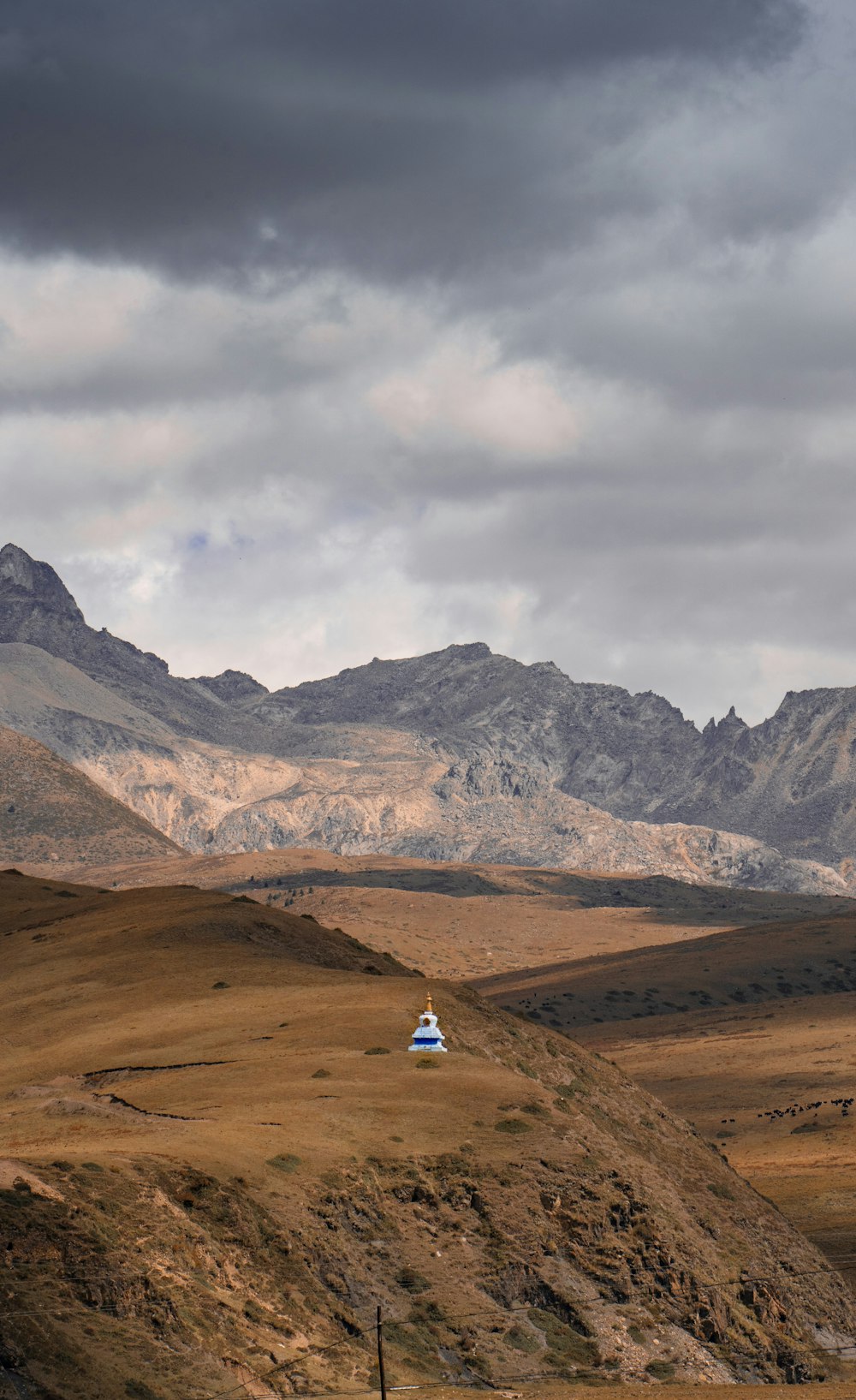 a small house in the middle of a field with mountains in the background