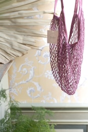 Bright green fluorescent crochet tote bag hanging on a white wall with soft natural light.