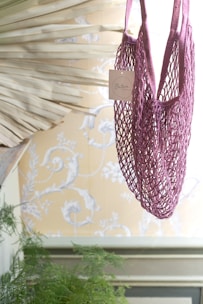 Bright green fluorescent crochet tote bag hanging on a white wall with soft natural light.