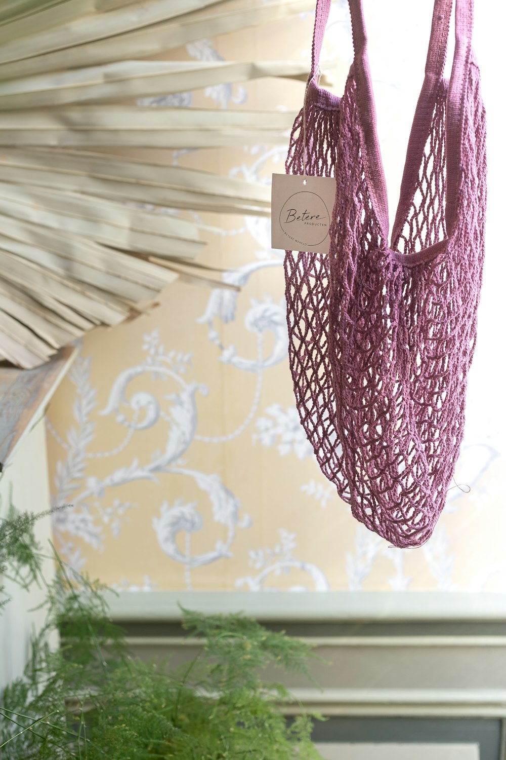 Eine lila Tasche, die neben einer Topfpflanze von der Decke hängt