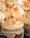 Cupcakes with creamy, swirled white frosting topped with orange and chocolate sprinkles. The cupcakes have a textured, rustic icing base.