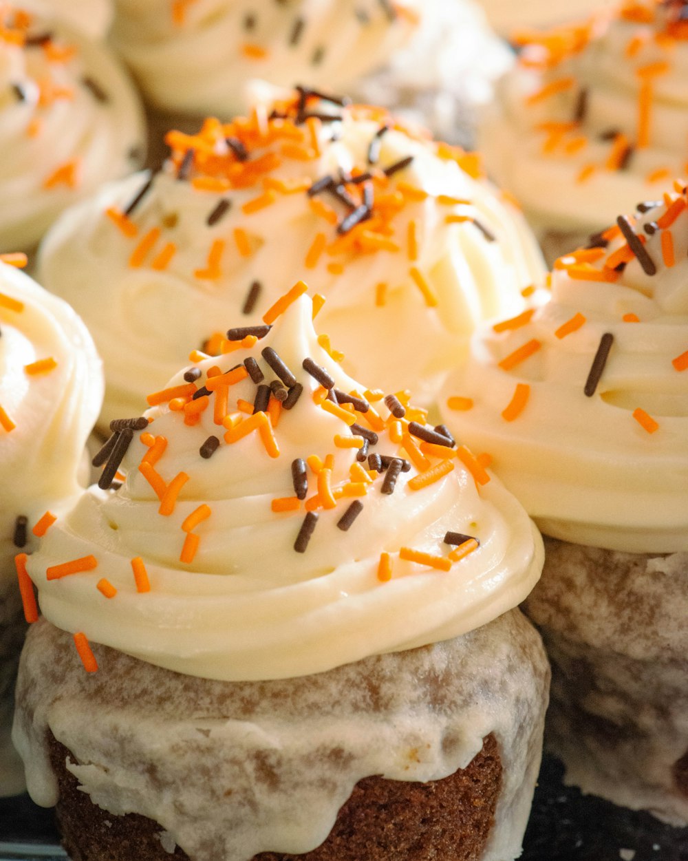 a plate of cupcakes with white frosting and sprinkles