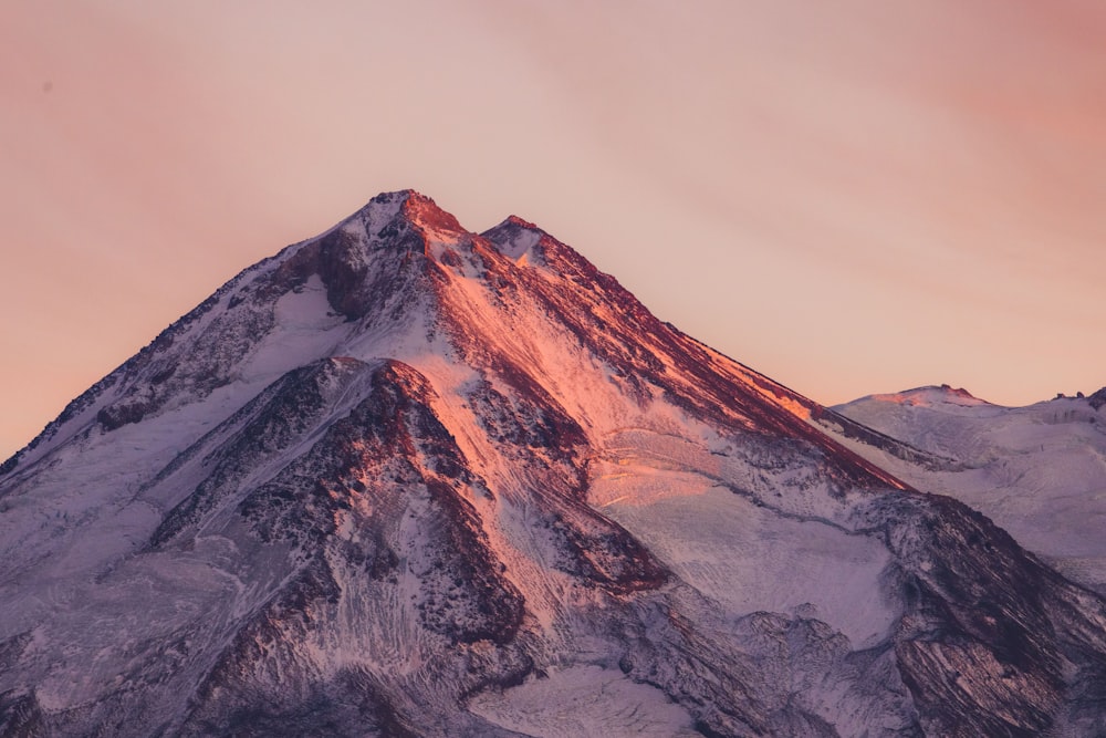 a snow covered mountain with a pink sky in the background